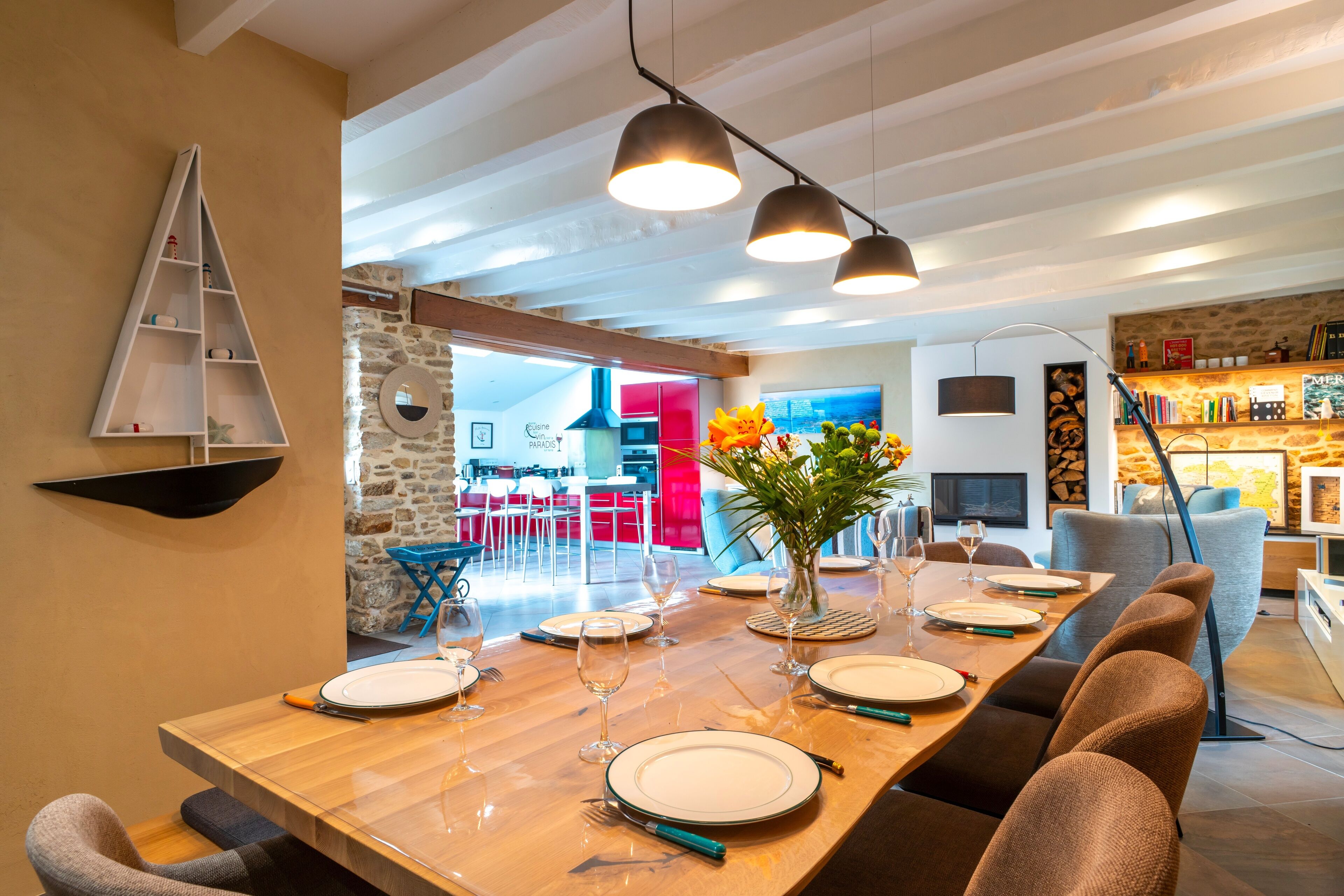A dining area with a wooden table set for six, modern chairs, and pendant lighting.