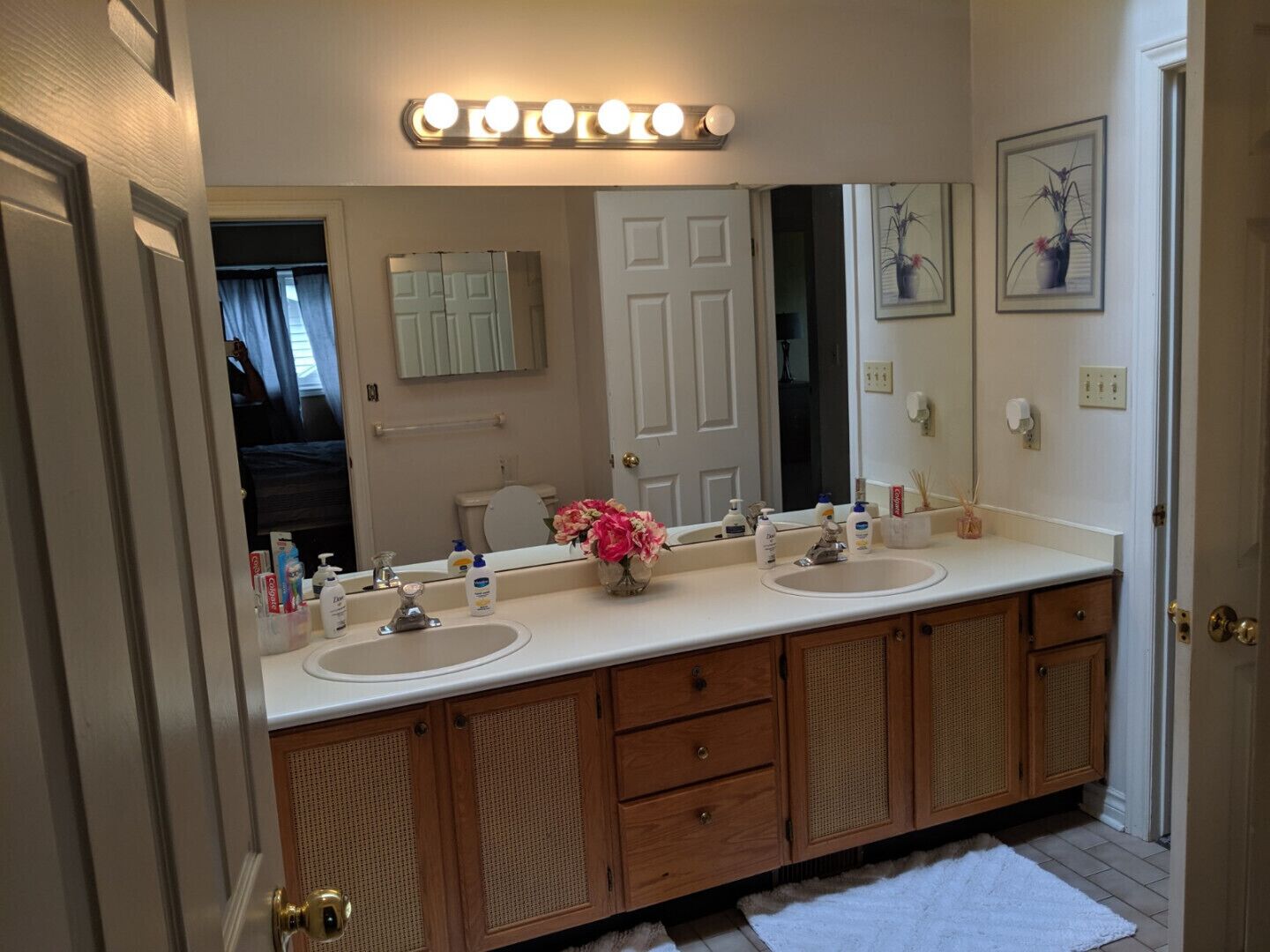 A bathroom with a double sink vanity, a large mirror, and a vanity cabinet.