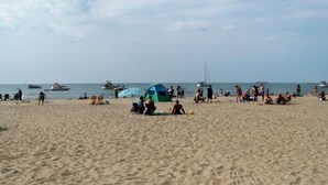 En strand med folk, tält och båtar.