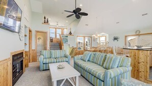 Ein geräumiger Wohnbereich mit einem gestreiften Sofa, einem weißen Couchtisch und einem Kamin.