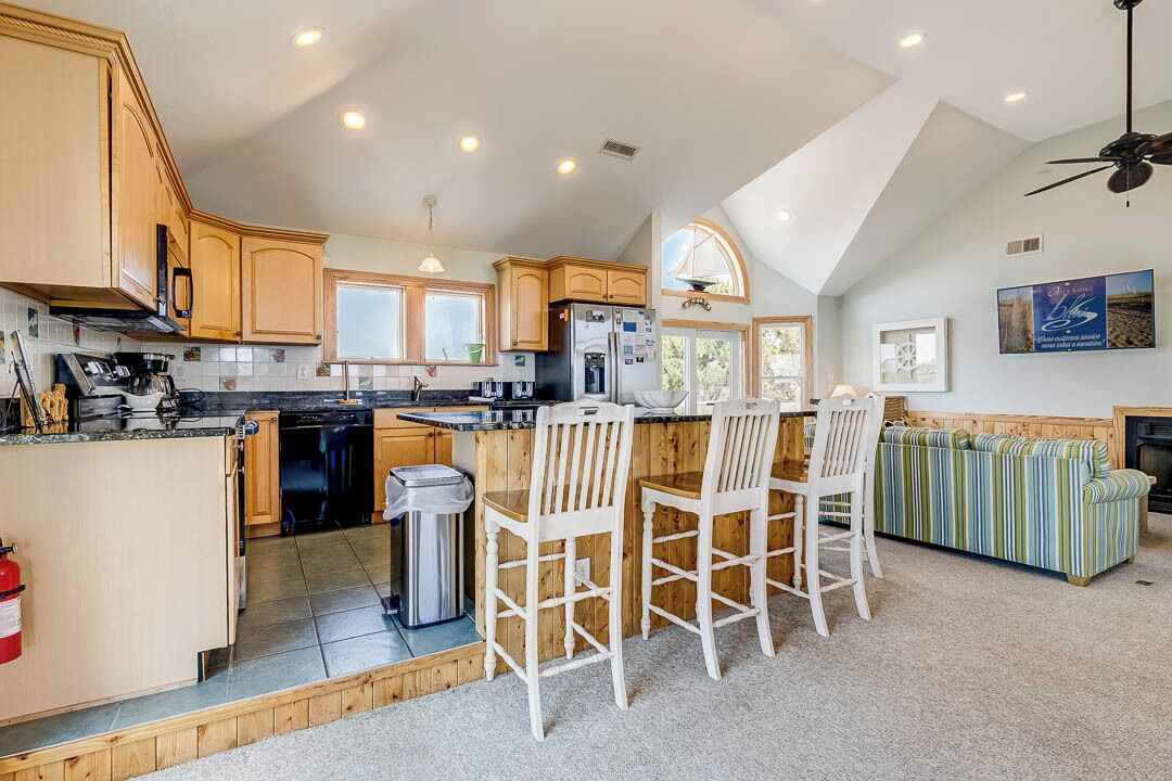 A spacious kitchen with wooden cabinets, a central island, and a dining area with white chairs.