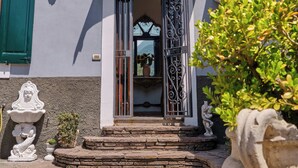 Un edificio con un acceso adoquinado de piedra, una puerta de madera y un arco decorativo.
