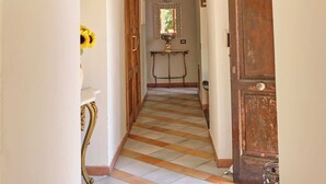 Un pasillo con piso a cuadros, una puerta de madera, un espejo y un cuadro enmarcado en la pared.