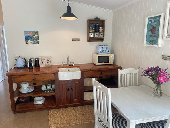 A compact kitchen with a wooden countertop, a built-in sink, a microwave, and a hanging light fixture. - Romantic Matakana Valley Barn Apartment (Matakana)