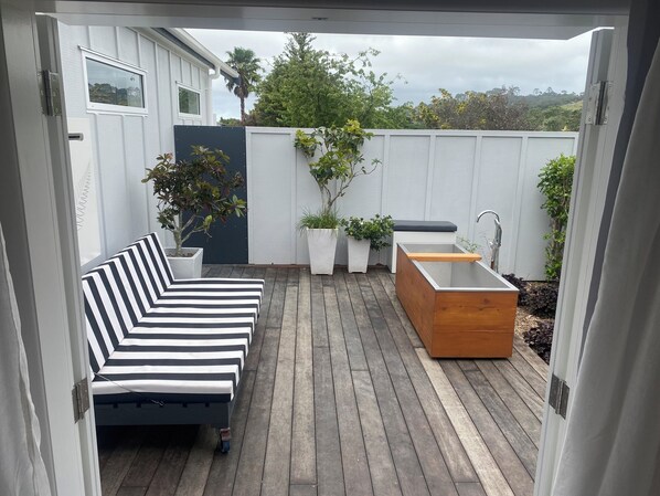 A deck with a black and white striped sofa, a wooden planter, and a built-in sink.