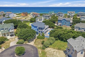 Una zona residencial costera con casas, un edificio azul grande y vistas al océano.
