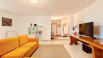 Un salon avec un canapé, une table basse en bois, un téléviseur et une bibliothèque.