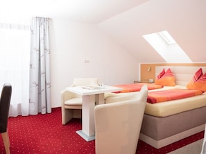 A hotel room with a bed, a small table, a chair, and a window with curtains. - Double Room with Balcony and Garden View - Pension Irlingerhof *** (Guggenberg)