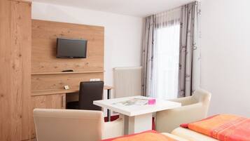 Ein Hotelzimmer mit Bett, Schreibtisch, Stuhl, Fernseher und einem Fenster mit Vorhängen.