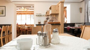 Ein Esstisch mit weißer Tischdecke, Salz- und Pfefferstreuern, einer weißen Tasse und einem Untertasse.
