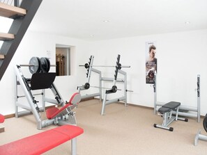 Ein Fitnessraum mit Gewichtstrainingsgeräten, einer Bank und einem Poster an der Wand.