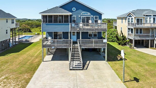 A two-story building with a balcony on the second floor, a staircase leading to the entrance, and a small front yard.