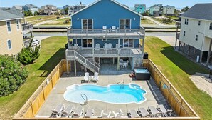 A two-story house with a balcony, a swimming pool, and outdoor seating.