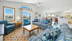 A spacious living room with a large sofa, a coffee table, and a dining area with chairs.