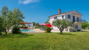 Une maison à deux étages avec une piscine, un patio couvert et une pelouse bien entretenue.