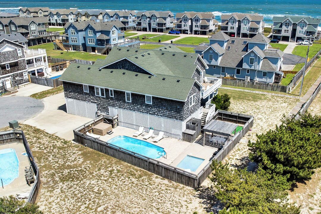 Una propiedad frente al mar con una casa grande, piscina y zona de terraza.