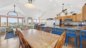 Uma cozinha ampla com armários de madeira, uma ilha grande e banquetas azuis.