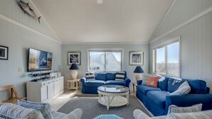 Un salon avec un canapé bleu, une table basse et un téléviseur posé sur un meuble.
