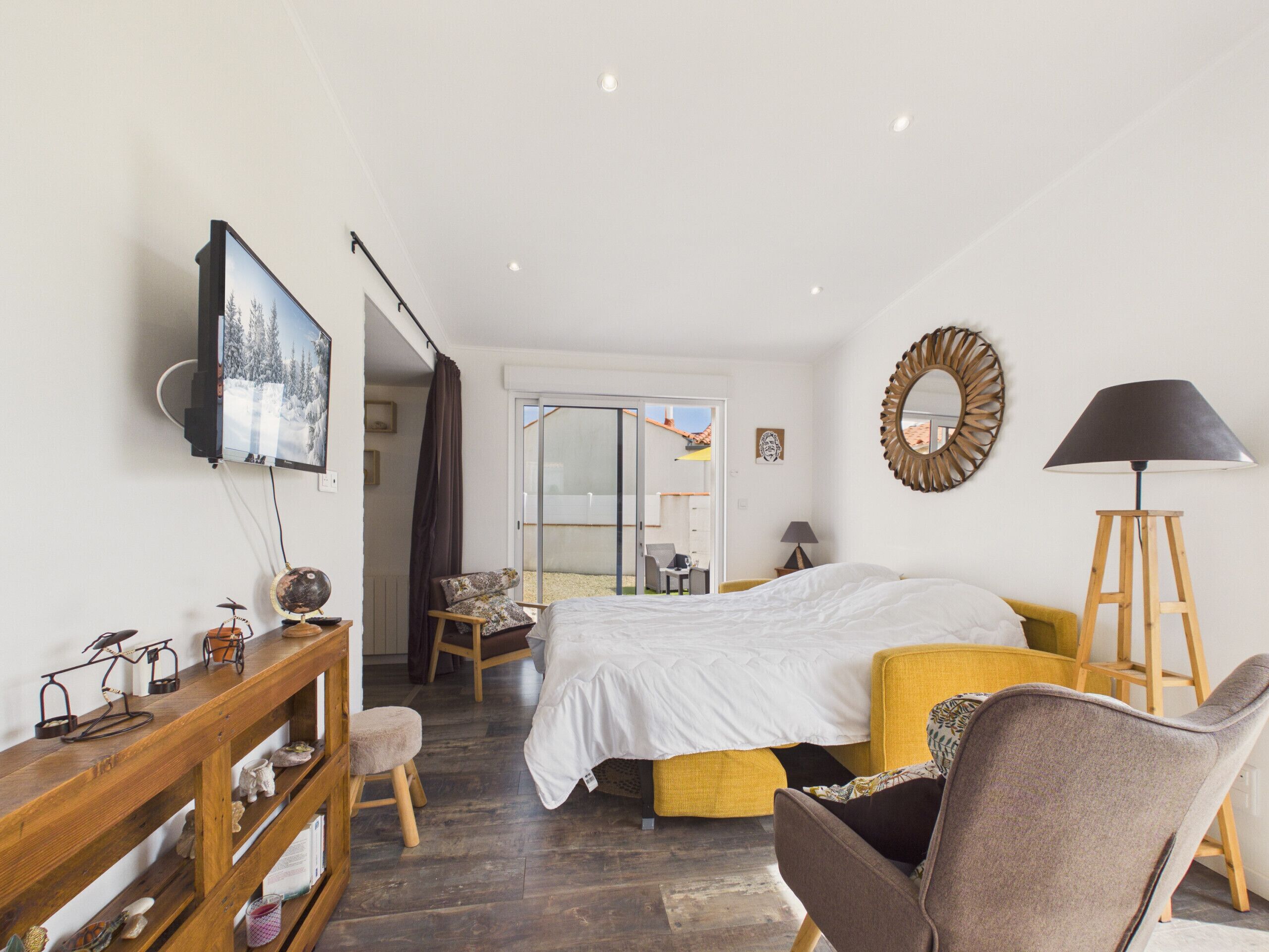 A bedroom with a bed, a desk, a chair, a lamp, and a television.