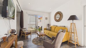 Ein Wohnzimmer mit einer Couch, Sesseln, einem Couchtisch, einem Fernseher, einem Globus und einer Lampe.