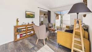 Ein modernes Wohnzimmer mit einer Couch, einem Sessel, einer Holzkommode, einem Fernseher und einer Leiter.