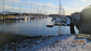 A marina with boats docked, a pier, and a bridge.