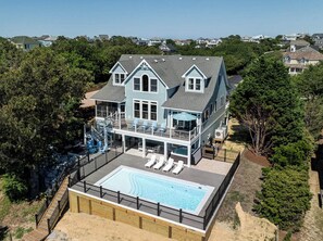 A large two-story house with a swimming pool, a deck, and a view of the surrounding neighborhood.
