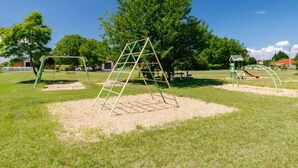 Ein Spielplatz mit Klettergerüst, Schaukeln und Rutsche.