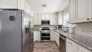 A kitchen with white cabinets, a stainless steel refrigerator, a microwave, an oven, and a sink. - Gilbert Home, Walk to Downtown, Restaurants, Nightlife 10+ location! (Gilbert)