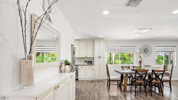 A modern kitchen with white cabinets, a dining area with wooden chairs, and a large window with blinds. - Gilbert Home, Walk to Downtown, Restaurants, Nightlife 10+ location! (Gilbert)