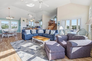 A spacious living room with a blue sofa set, a wooden coffee table, and a patterned rug.