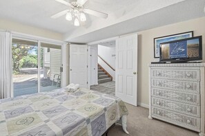 A bedroom with a bed, a dresser, a television, and a staircase leading to another room.