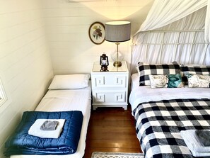 Un dormitorio con dos camas, una mesita de noche con lámpara y un marco decorativo.