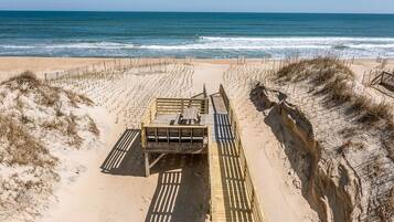 A beach with a wooden walkway leading to a gated entrance.