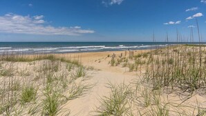 A beach with sand dunes and sparse vegetation. - Glistening Sands | Oceanfront | Private Pool, Hot Tub | Nags Head (Nags Head)