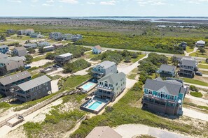 A coastal residential area with houses, a swimming pool, and a beach access walkway.