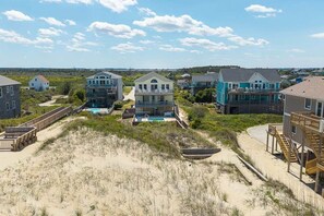 Zona residencial costera con casas, una playa de arena y un paseo marítimo de madera.