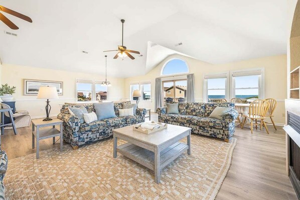 A spacious living room with two patterned sofas, a coffee table, and a ceiling fan.