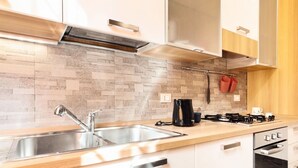 A modern kitchen with a stainless steel sink, a gas stove, and white cabinetry.