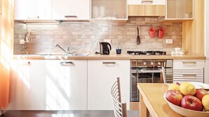 A modern kitchen with white cabinets, a tiled backsplash, a gas stove, and a dining area with a table and chairs.