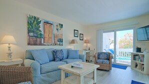 A living room with a blue sofa, a coffee table, wicker chairs, and a bookshelf.