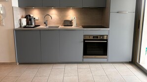 Eine moderne Küche mit grauen Schränken, einem eingebauten Backofen und einem Toaster.