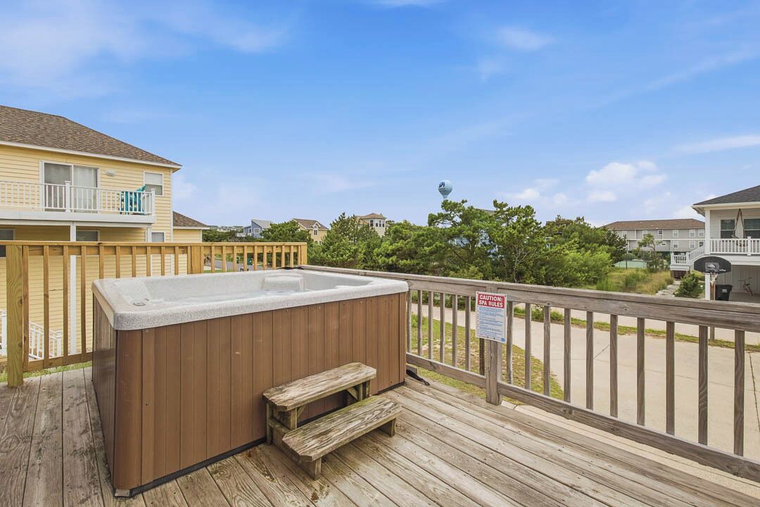 A wooden deck with a hot tub, a wooden bench, and a sign indicating spa rules.