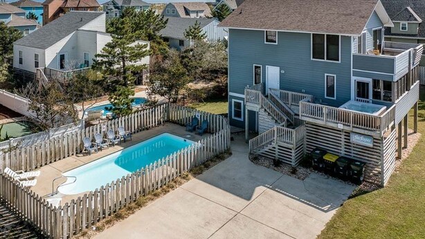 Uma casa de dois andares com quintal cercado, piscina e deck.