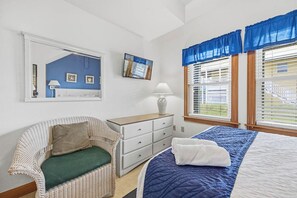 A bedroom with a bed, a chair, a dresser, and a window with blinds.