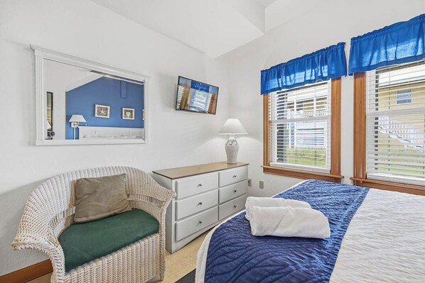 A bedroom with a bed, a chair, a dresser, and a window with blinds. - Sea Scapes | 817 ft from the beach | Private Pool, Hot Tub | Corolla (Corolla)