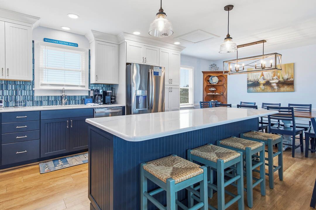 A kitchen with a large island, bar stools, and a dining area with a table and chairs.