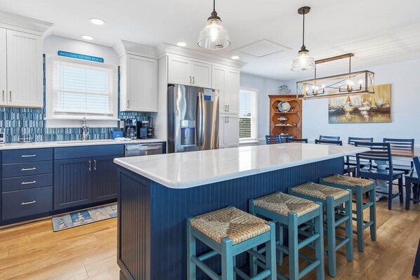 A kitchen with a large island, bar stools, and a dining area with a table and chairs.