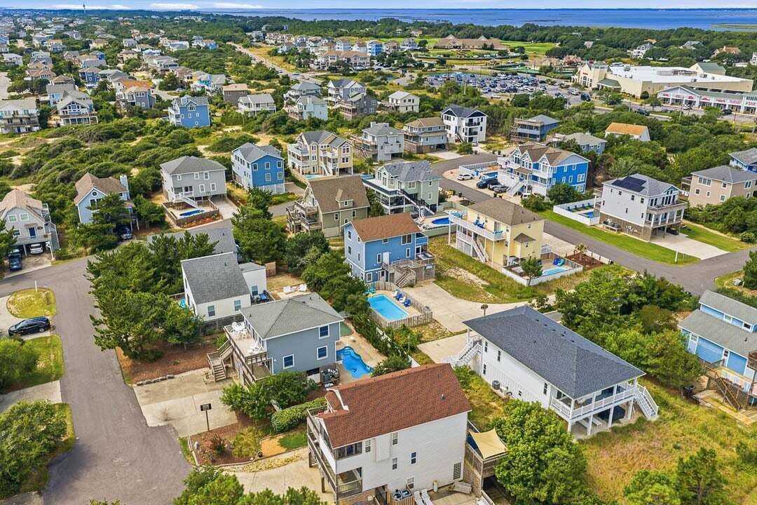Un barrio residencial con casas, una piscina y vistas al océano.