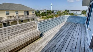 Um deck de madeira com guarda-corpo, com vista para uma área residencial com casas e um reservatório d'água.